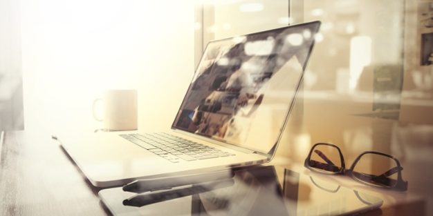 Office workplace with laptop and smart phone on wood table and london city blurred background