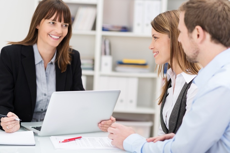 Young couple sitting in an office talking to a woman broker or investment adviser.jpeg